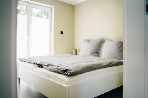 a white bed in a room with a window at Ferienhaus Küstennebel - Ostseewelle mit Sauna in Ostseebad Koserow