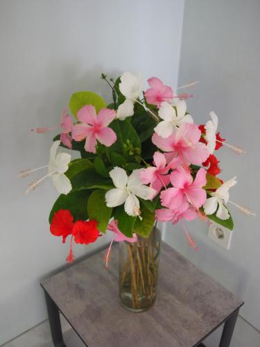 a vase filled with pink and white flowers on a table at La Quoriena Botanical Villa & Cafe' in Labuan Bajo