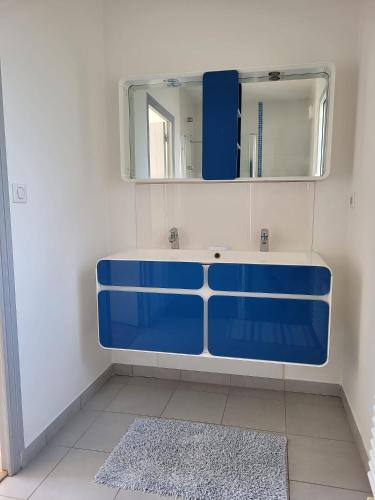 La salle de bains est pourvue d'un lavabo bleu et d'un miroir. dans l'établissement VILLA FAMILIALE Bord de Mer, à Beg-Meil