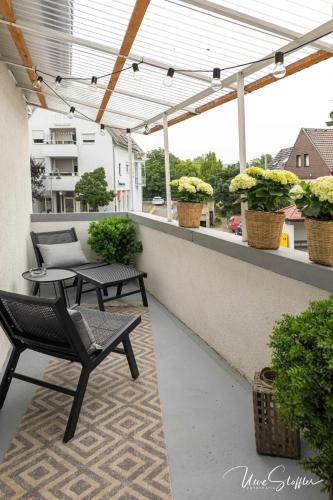 a patio with chairs and potted plants on a balcony at Sali Homes - Bergerie in Obersulm