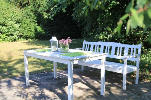 a white table and a bench with flowers on it at Ferienwohnung Naturfreund in Lügde