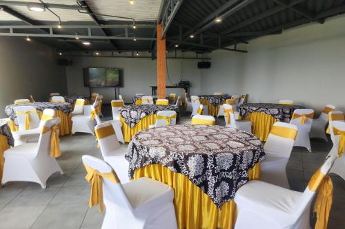 a room with tables and white chairs and a stage at Alinson Sunset Hill in Bogor
