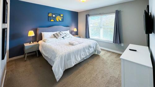 a blue bedroom with a bed and a window at Dream Townhouse with Splash Pool at Le Reve 4439 in Kissimmee
