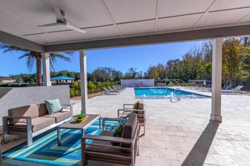 a patio with a couch and chairs and a pool at Dream Townhouse with Splash Pool at Le Reve 4439 in Kissimmee