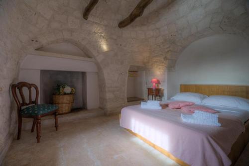 a bedroom with a large bed and a chair at Trullo Casa Surya in Martina Franca