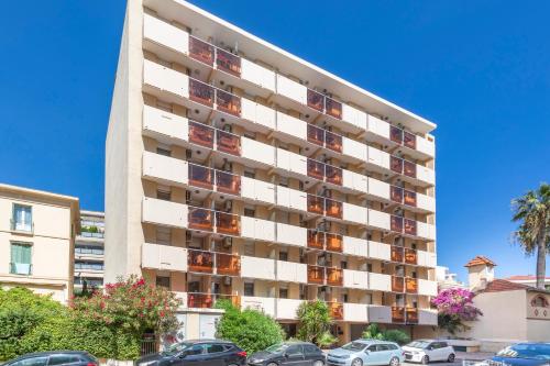 a tall apartment building with cars parked in front of it at Résidence Pierre & Vacances La Promenade des Bains in Saint-Raphaël