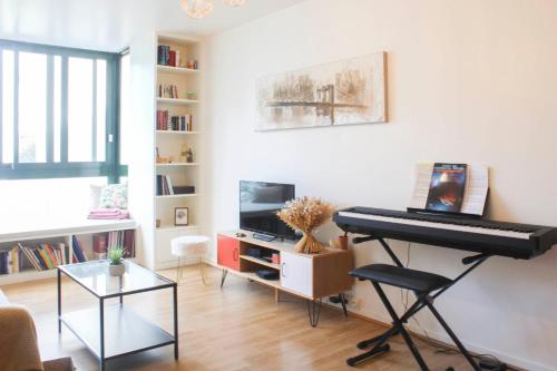 - un salon avec un piano et une télévision dans l'établissement 1 bedroom apartment with garden, à Asnières-sur-Seine