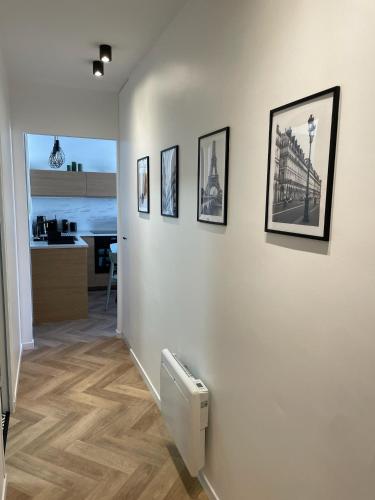 a hallway with a white wall with pictures on it at New fully equiped appartment with parking in Saint-Mandé