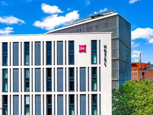 a large white building with a pink sign on it at Ibis Hamburg City in Hamburg