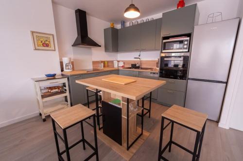 une cuisine avec une table en bois et un réfrigérateur dans l'établissement T3 neuf 5 minutes des plages garage privé, à Dinard