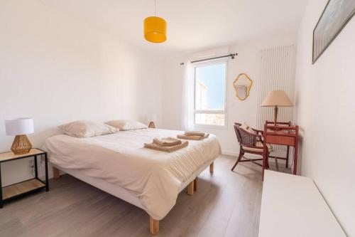 a white bedroom with a bed and a desk at T3 neuf 5 minutes des plages garage privé in Dinard