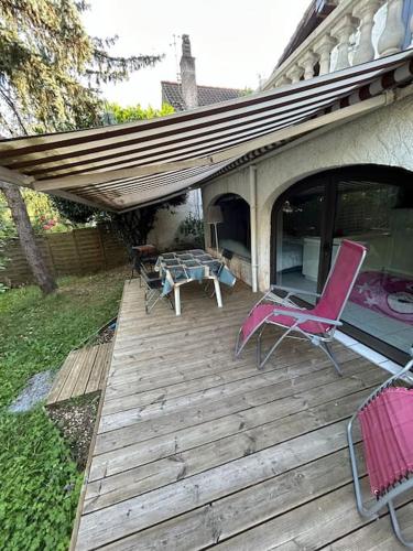 une terrasse en bois avec deux chaises et une table dans l'établissement Charmant t2 dans une belle villa avec sa grande piscine, à Brive-la-Gaillarde