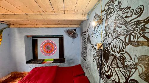 a bedroom with a red bed and a painting on the wall at Memoir Homestay in Kasol