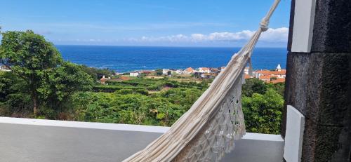 a hammock on a balcony overlooking the ocean at Adega Melo Pereira - 2 quartos com vista mar in São Roque do Pico