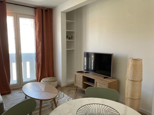een woonkamer met een televisie en een tafel en stoelen bij New fully equiped appartment with parking in Saint-Mandé