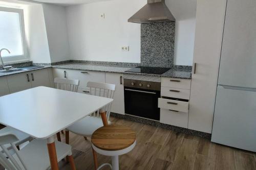 a kitchen with a white table and a white refrigerator at Casa Sáner in Rábade