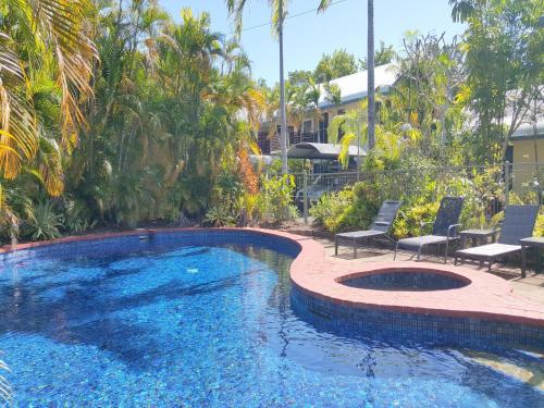 a swimming pool with two chairs and a patio with a swimming pool at Mango Tree Holiday Apartments in Port Douglas