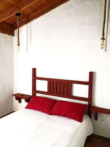 a bedroom with a bed with red pillows on it at La Carpintería nature relax in Tefía