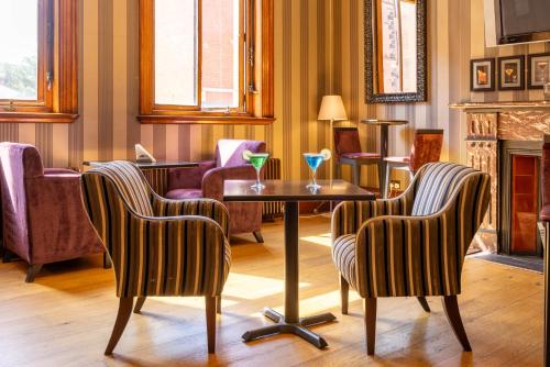 a living room with two chairs and a table with drinks on it at Cathedral Quarter Hotel - Derby in Derby