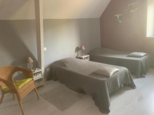 une chambre avec deux lits et une chaise et une fenêtre dans l'établissement La Vallée, à Feugères