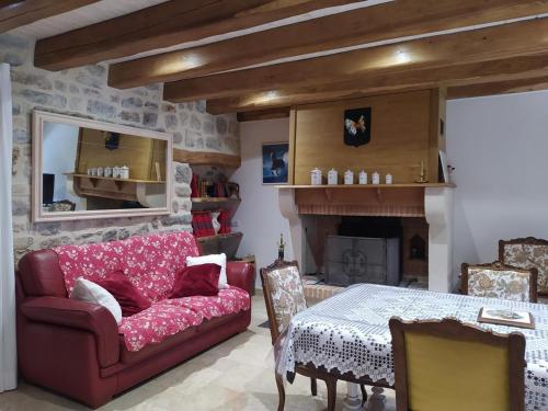 a living room with a red couch and a table at Gite de 12 personnes a molines in Saint-Étienne-du-Valdonnez