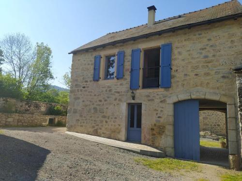 an old stone building with blue shutters and a garage at Gite de 12 personnes a molines in Saint-Étienne-du-Valdonnez