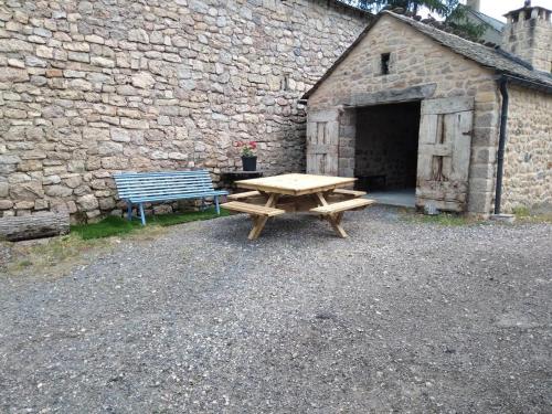 a wooden picnic table and a bench in front of a building at Gite de 12 personnes a molines in Saint-Étienne-du-Valdonnez