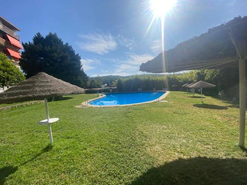 ein Pool mit einem Strohschirm im Hof in der Unterkunft La Herradura De San Pedro in Arenas de San Pedro