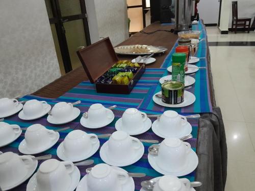 een tafel met kopjes en theepotten en een dienblad met eten bij Kibo Peak Palace Hotel in Morogoro