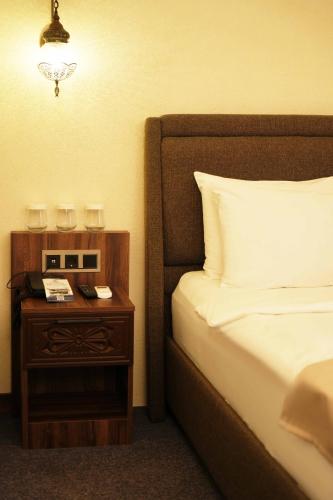 a bedroom with a bed and a nightstand with a clock at Rüstempaşa Kervansaray Hotel in Edirne