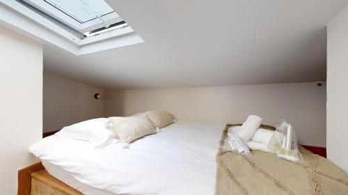 une chambre avec un lit blanc avec une lucarne dans l'établissement Bluestay 3 - Appartement au Cœur de Paris, à Paris