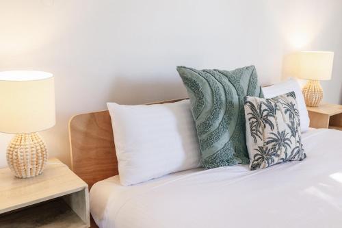 a bedroom with a bed with pillows and two lamps at Breezy Beach House - Private Pool in Yaroomba