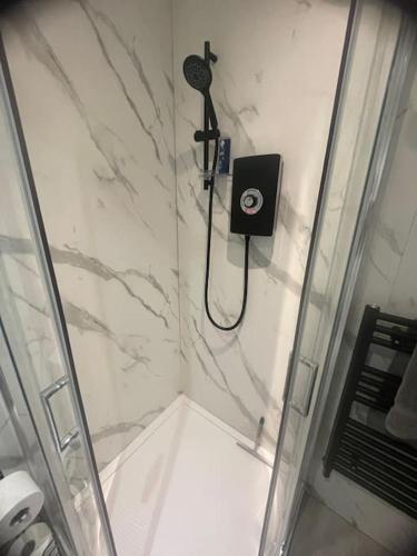 a bathroom with a shower with a phone on the wall at Private Studio near Watford Junction in Leavesden Green