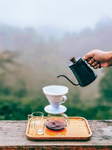 a person is holding a tea kettle on a tray at Ma Family Coffee Farm ไร่กาแฟครอบครัวมะ in Ban Huai Pong Nam Ron