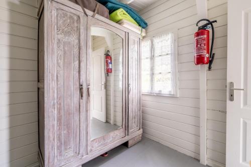 ein alter Holzschrank in einem Flur mit einem Spiegel in der Unterkunft Chalet face mer Pointe Saint Gildas in Préfailles