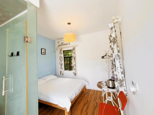a small bedroom with a bed and a table at Cloud Tree Inn Boutique Guesthouse XiChong DaPeng ShenZhen 深圳大鹏西涌云树里民宿Yun Shu Li in Shenzhen