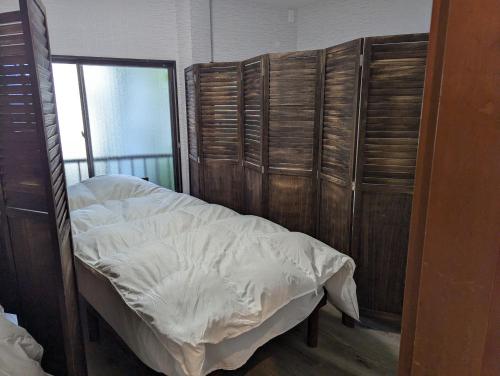 a bed in a room with wooden walls and bunk beds at 宿坊かつら in Izu