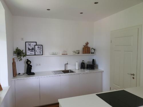 a white kitchen with a sink and a counter at Villa am Schloss in Werneck