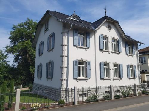 a white house with blue windows and a fence at Villa am Schloss in Werneck