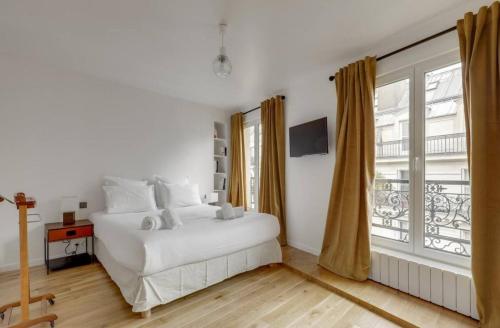 une chambre blanche avec un lit et une fenêtre dans l'établissement Spacious Apartment - 4B-8P - Sentier, à Paris