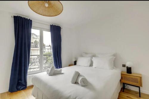 - une chambre avec un grand lit blanc et des rideaux bleus dans l'établissement Spacious Apartment - 4B-8P - Sentier, à Paris