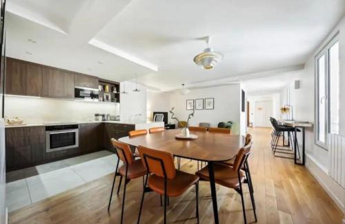 une cuisine et une salle à manger avec une table et des chaises en bois dans l'établissement Spacious Apartment - 4B-8P - Sentier, à Paris