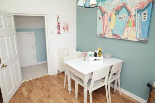 a dining room with a white table and a painting on the wall at Divine in Georgeham