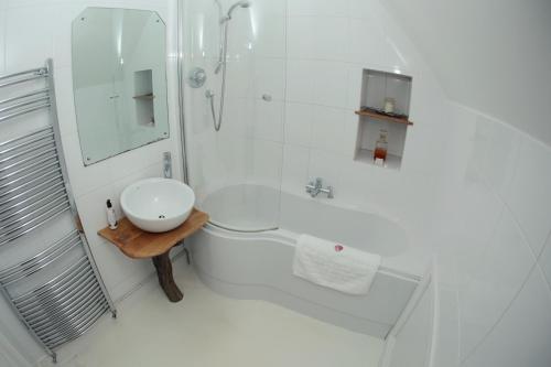 a white bathroom with a shower and a sink at Divine in Georgeham