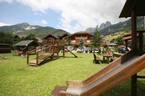 a playground in a park with mountains in the background at Hotel Sella Ronda Serenella in Campitello di Fassa