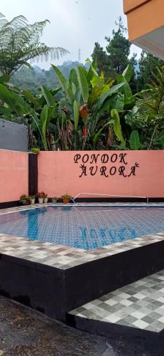 a swimming pool with a sign on a wall at Villa Pondok Aurora in Campaka