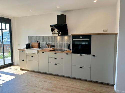 a kitchen with white cabinets and a sink and a microwave at Ferienwohnung Smukke Bleibe in Maasholm