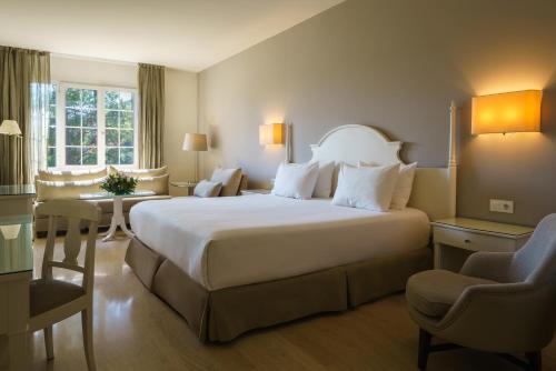 Una habitación de hotel con una cama grande y una silla. en Crisol Jardines de Córdoba, en Córdoba