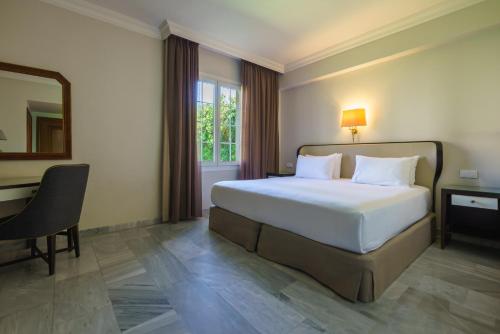 a bedroom with a bed and a desk and a mirror at Crisol Jardines de Córdoba in Córdoba
