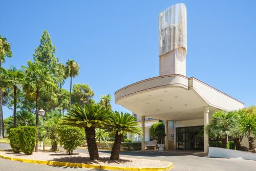 a building with palm trees in front of it at Crisol Jardines de Córdoba in Córdoba